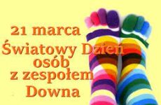 21 marca Światowy Dzień osób z zespołem Downa na żółtym tle dwie stopy w skarpetkach w paski róznokolorowych.